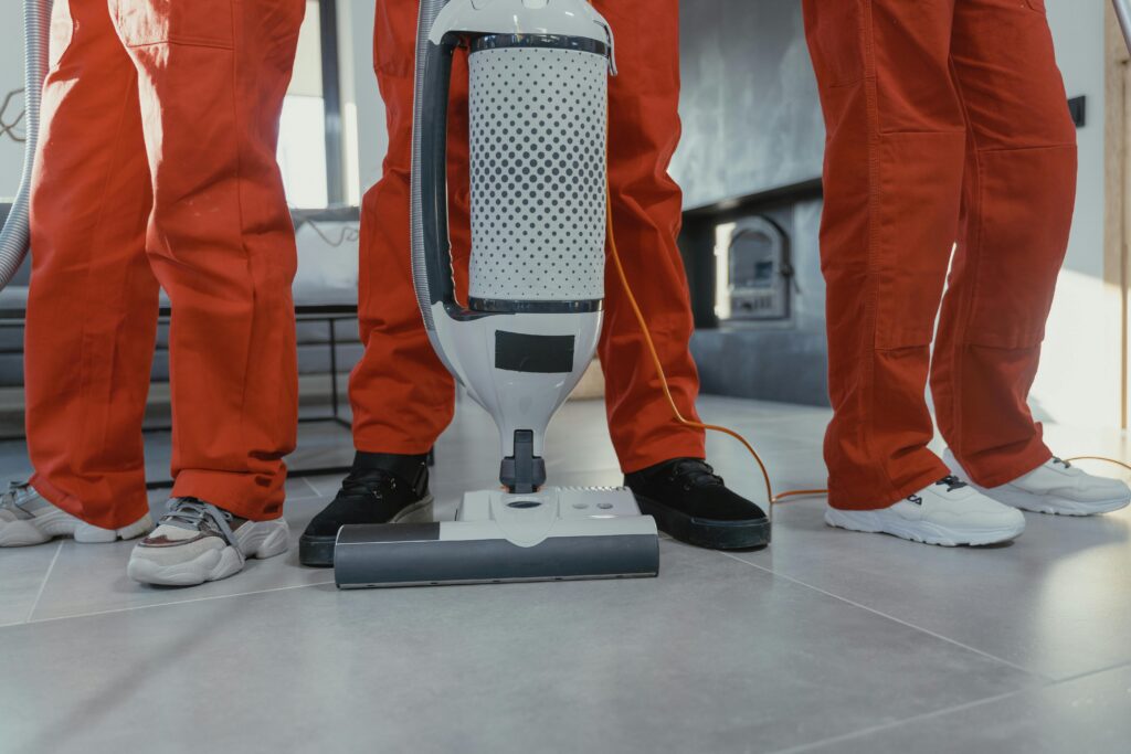 pexels photo 6195122 6195122 Team of professional cleaners in red uniforms using a vacuum cleaner indoors.