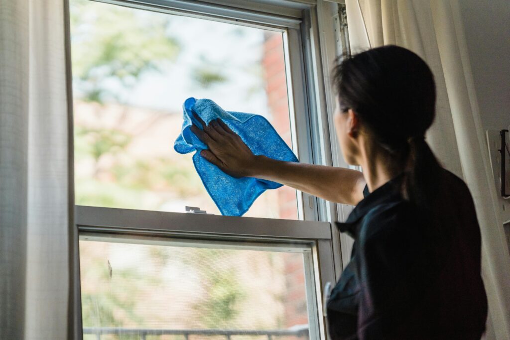 pexels photo 9462100 9462100 A woman cleans a window using a blue microfiber cloth providing a streak-free shine.